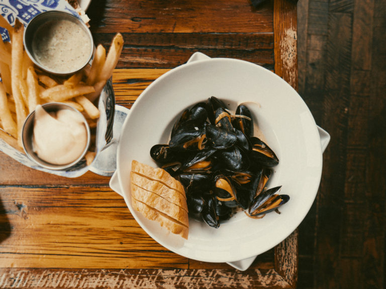 A steaming bowl of mussels served with a fry cone